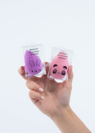 hand holding two makeup blending sponges, one purple and one pink
